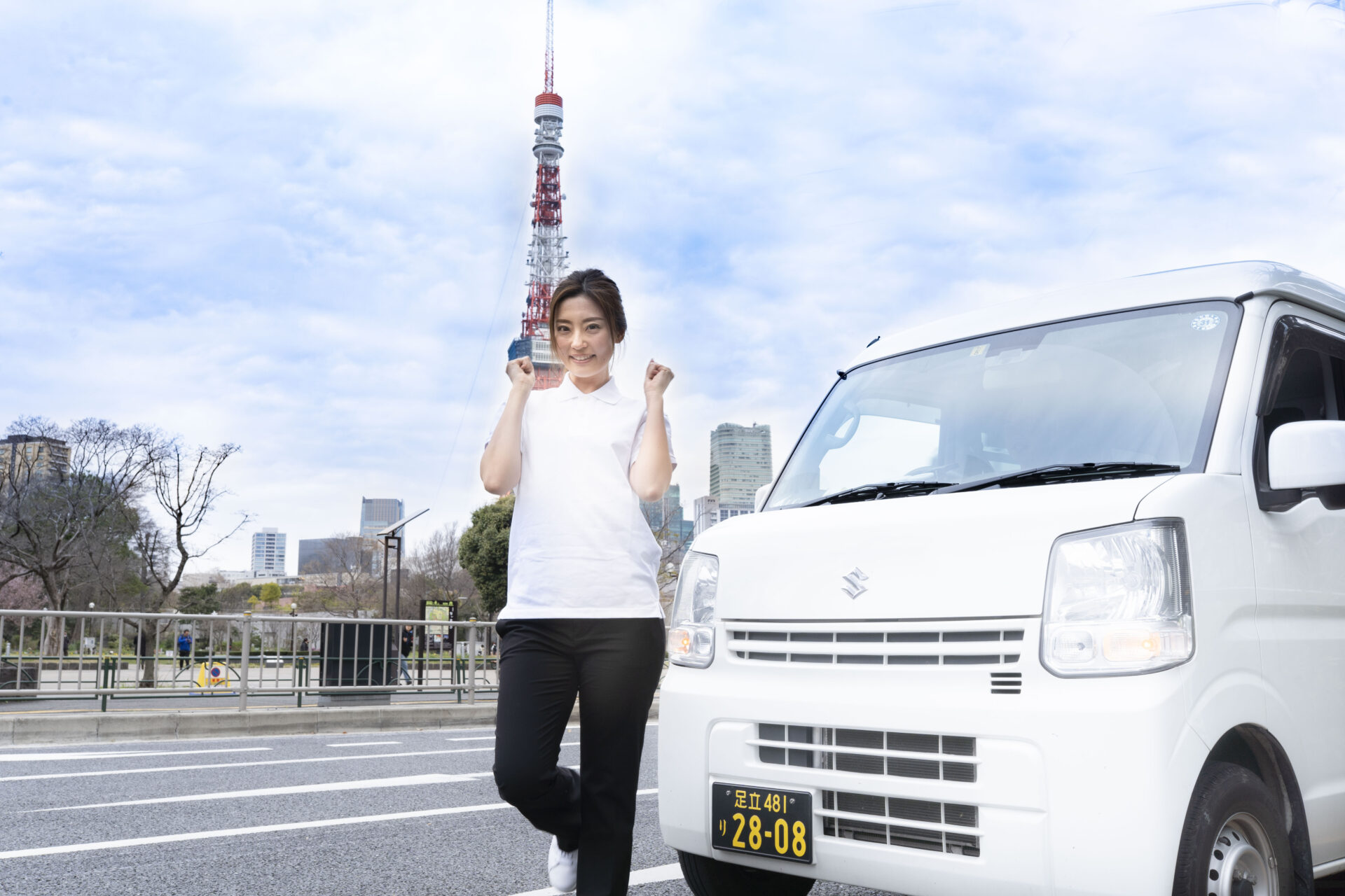 東京タワーをバックにポーズを取る若い女性ドライバー